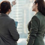 Two confident businesswoman having a discussion in front of modern corporate skyscrapers