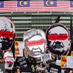 Protesters hold cut-out boards of the head of the former